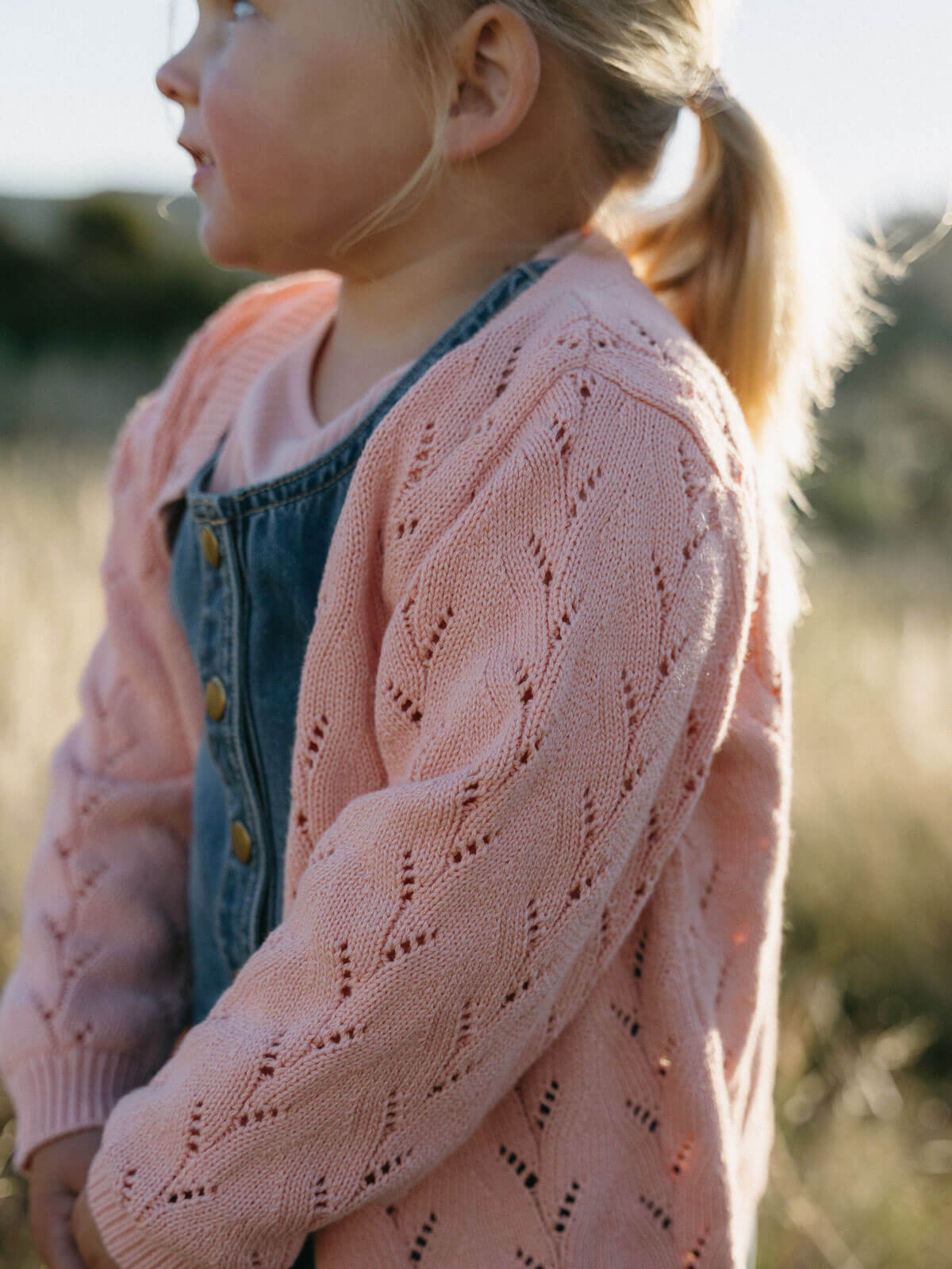 Child wearing a pink cardigan in an outdoor setting