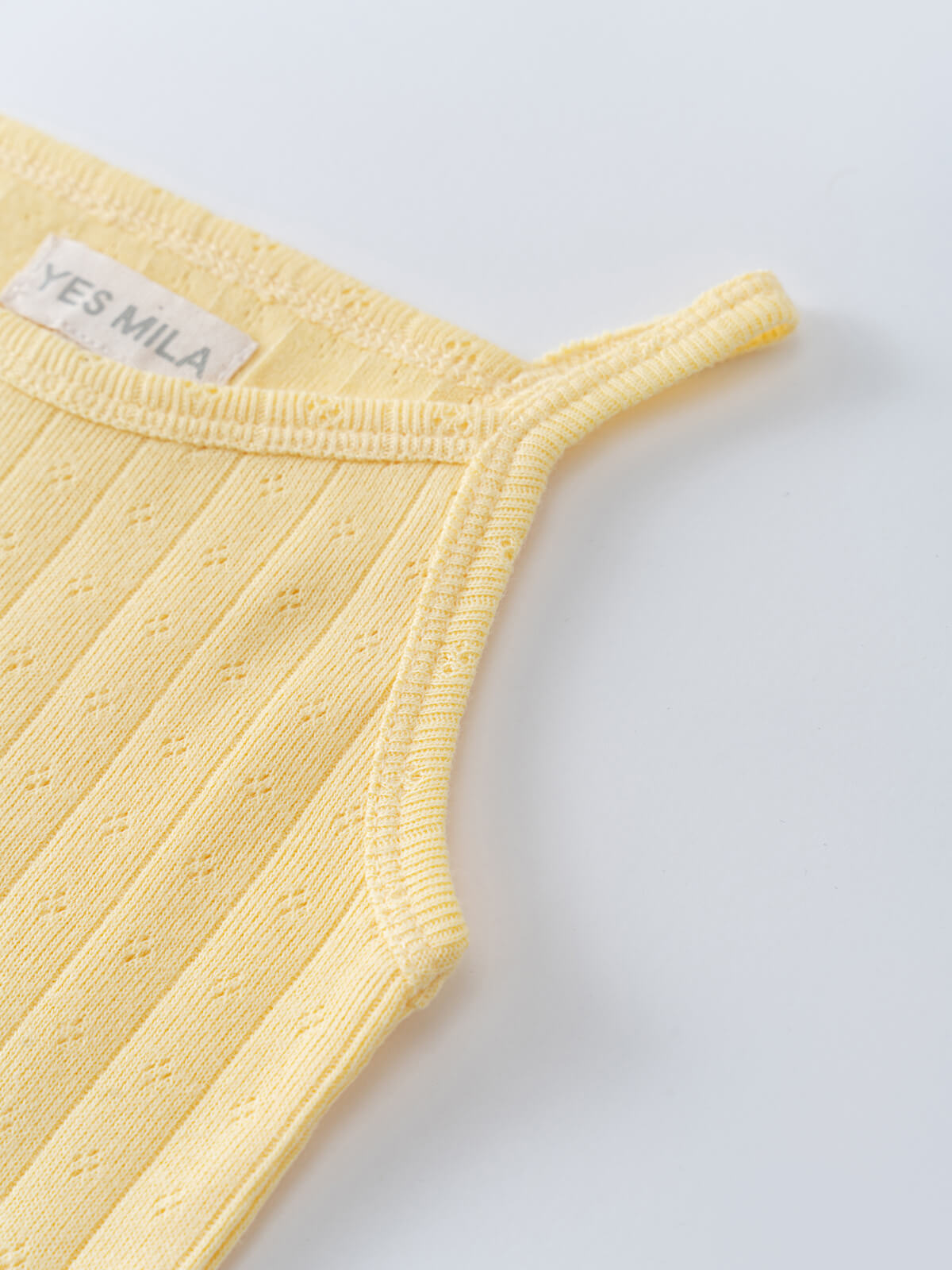 Close-up of a pale yellow ribbed knit garment with brand label pointelle Singlet Bodysuit - Sun Soaked Baby girl