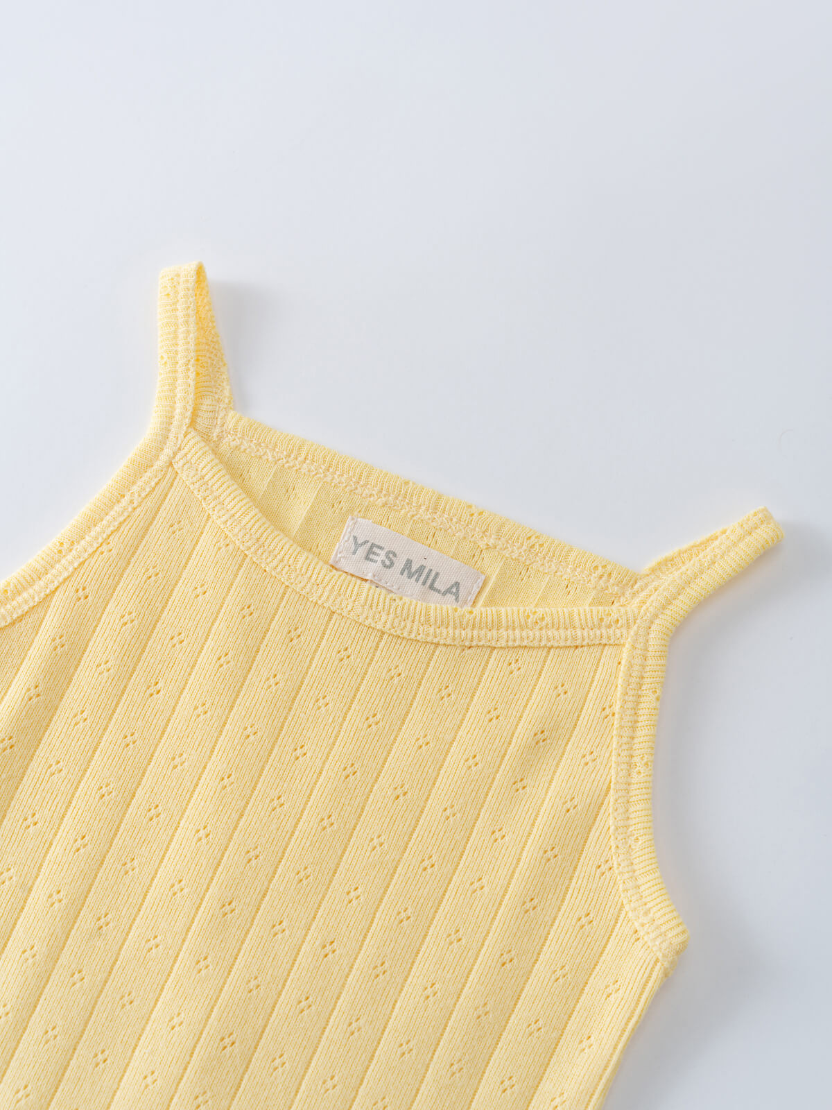 Close-up of yellow ribbed knit bodysuit with thin straps and label Pointelle Singlet Bodysuit - Sun Soaked Baby girl