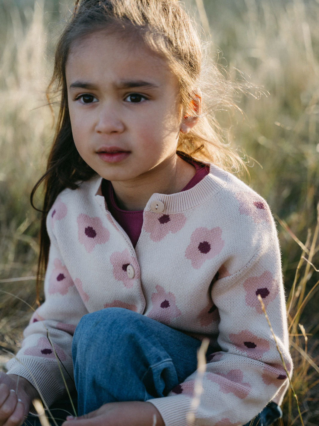Young girl sitting in tall grass wearing a floral patterned cardigan Printed Cardigan - Bold Daisy Girls