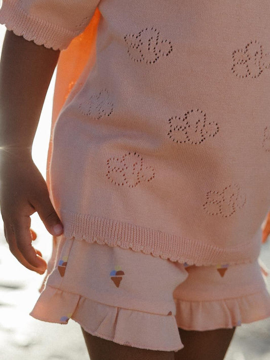 a little girl wearing a peach shots with small prints of ice-cream