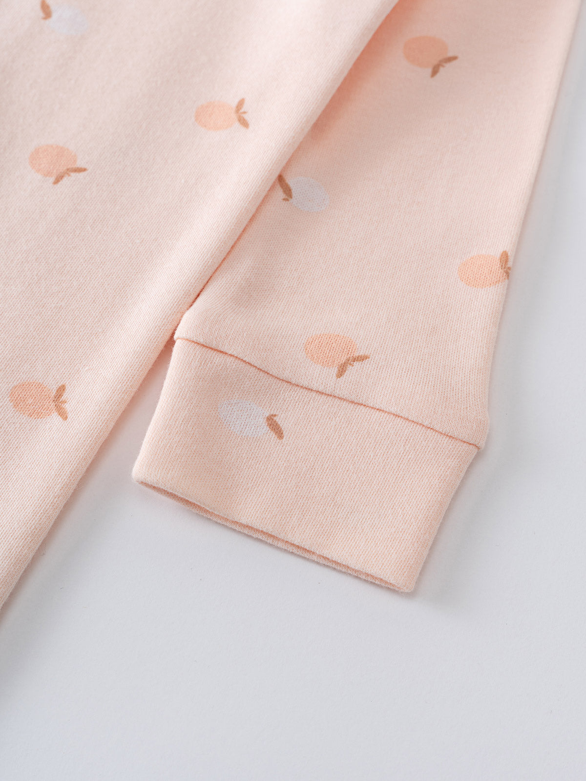 Close-up of peach fabric sleeve with small apple print pattern Printed Long Sleeve One Piece - Apples Baby girl