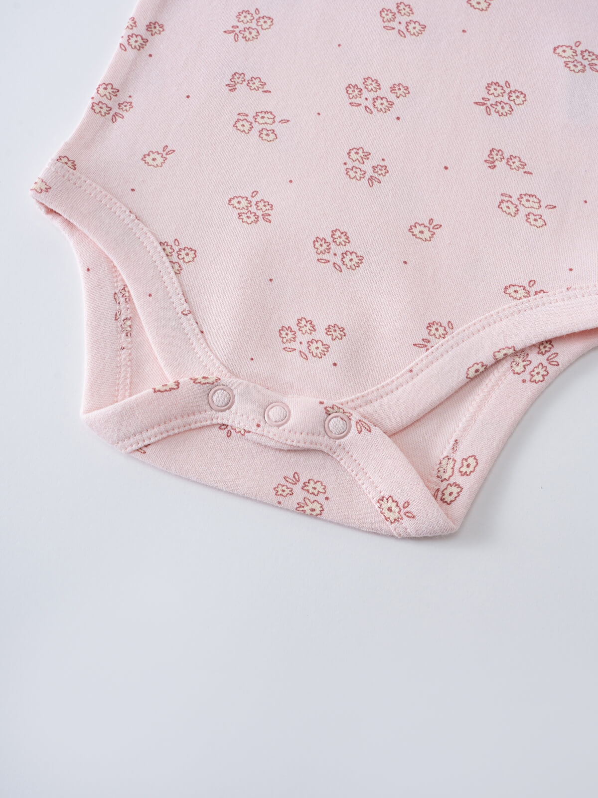 Close-up of pink baby bodysuit with floral print and snap closures Printed Short Sleeve Bodysuit - Daisy Chain Baby girl