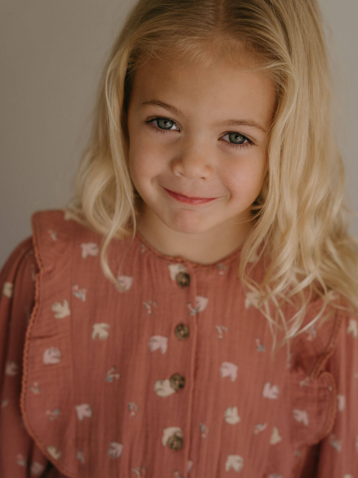 Young girl with blonde hair wearing a patterned dress against a neutral background Printed Woven Dress - Bird And Blossom Rosehip Girls