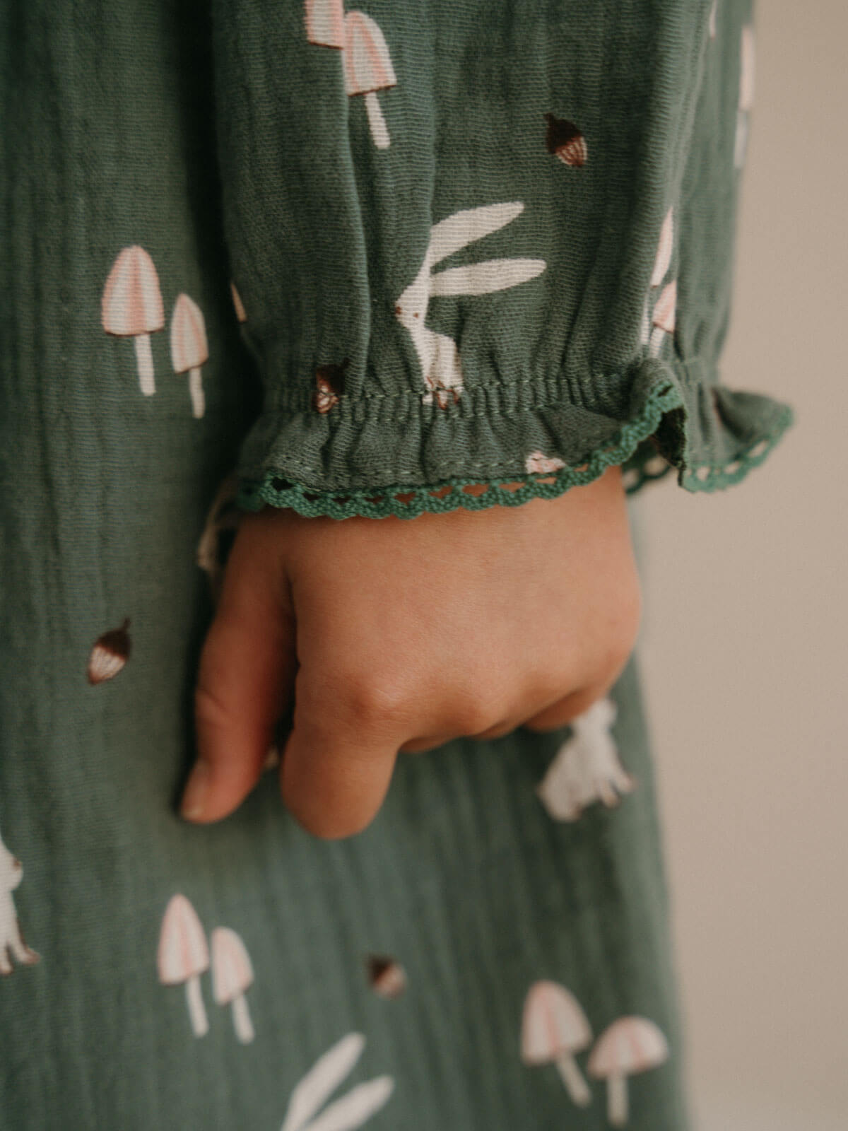 Hand holding a green fabric with mushroom and rabbit pattern Printed Woven Dress - Forest Gathering Balsam Girls