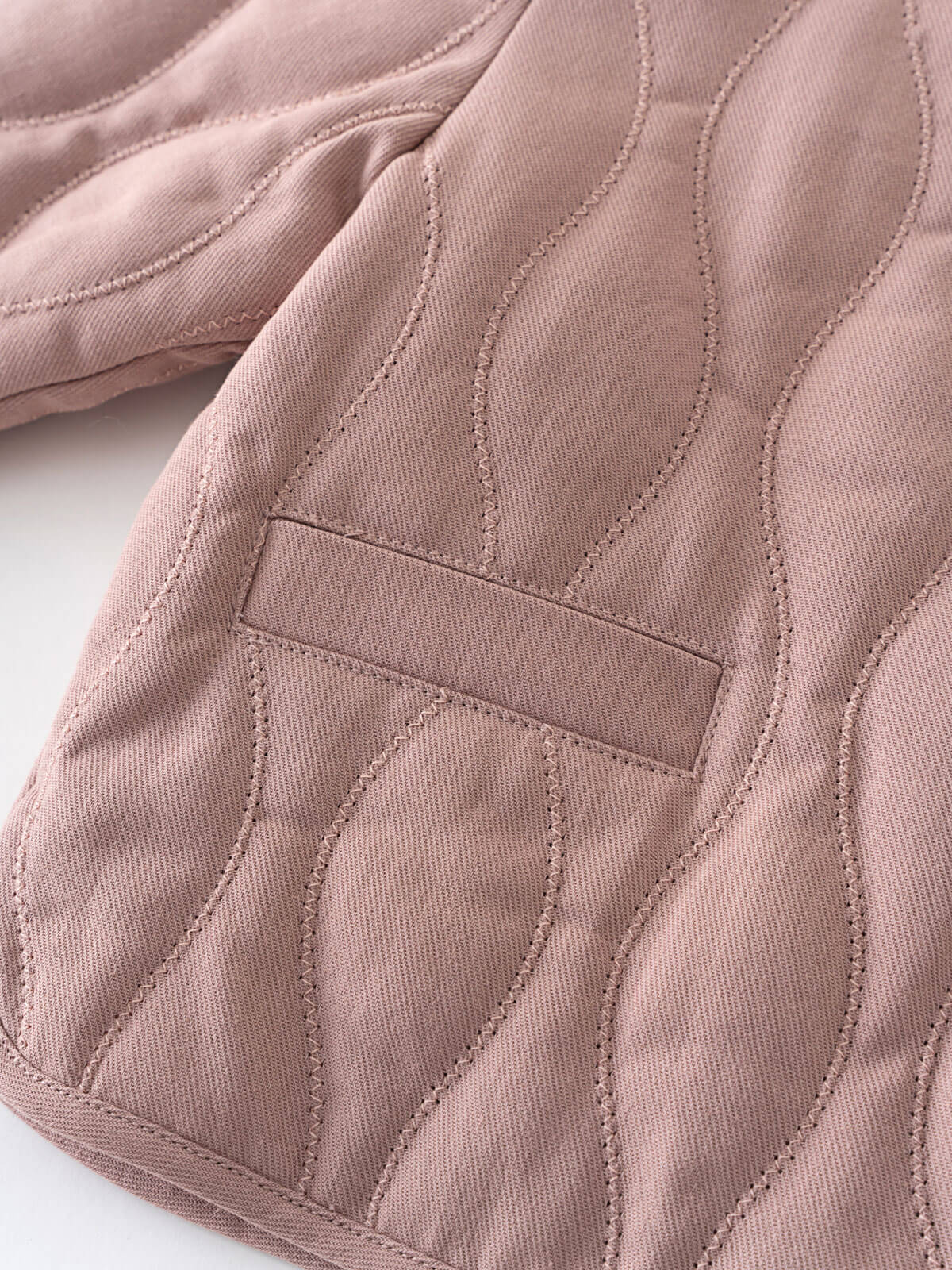 Close-up of a quilted pink jacket with stitching details on a white background Quilted Jacket - Blush Baby girl