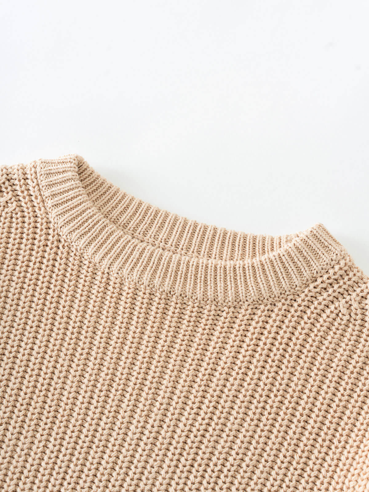 Close-up of a beige knitted sweater on a white background