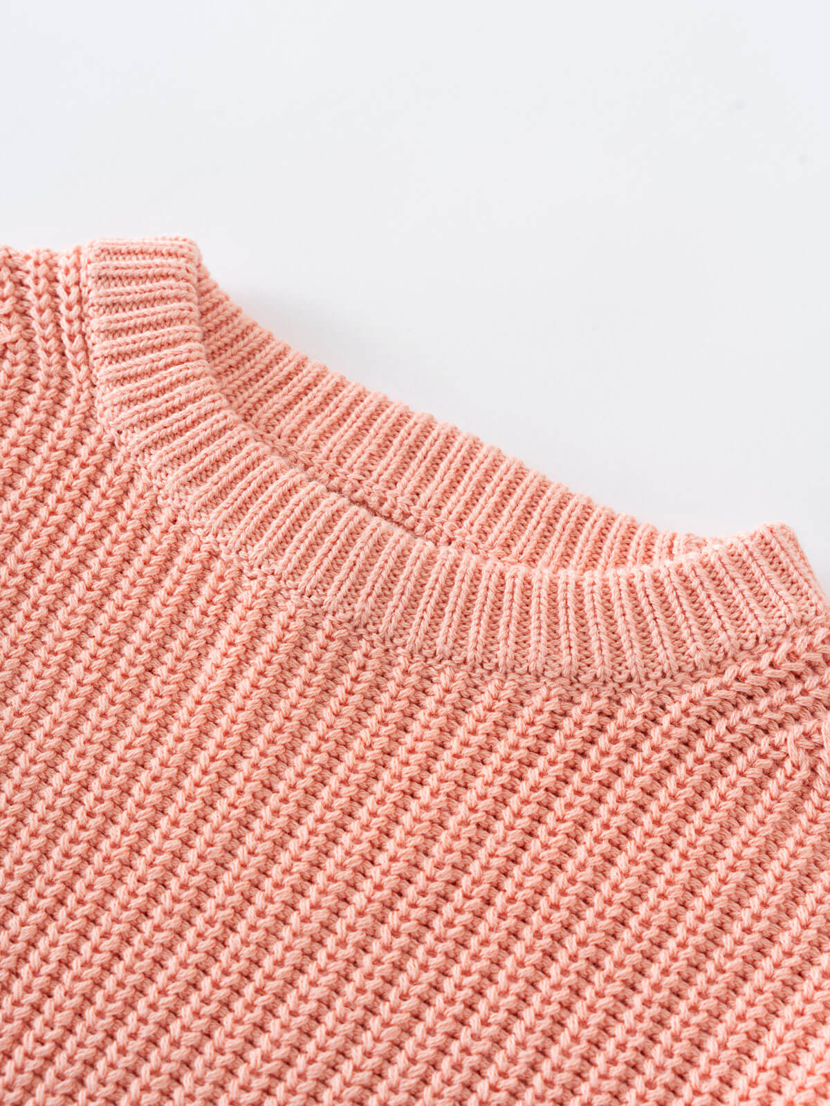 Close-up of a pink knitted sweater on a light gray background