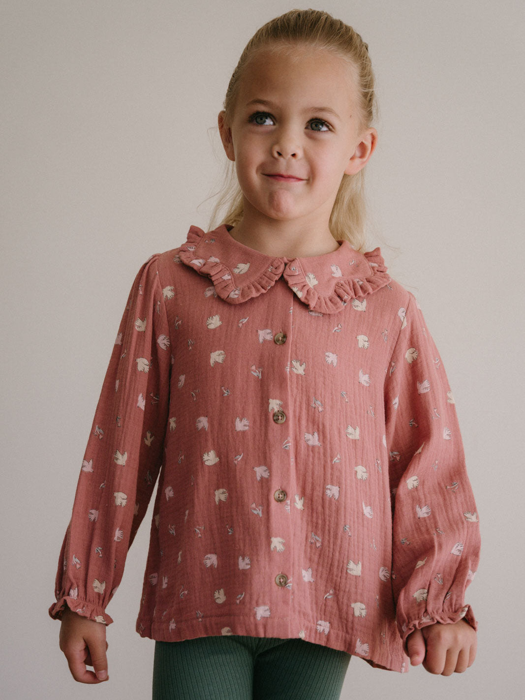 Young girl wearing a pink patterned button-up blouse with ruffled collar Ruffle Woven Blouse - Bird And Blossom Rosehip Girls