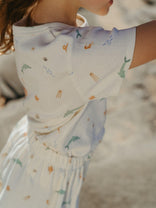 Close-up of a child wearing a white dress with colorful patterns on a blurred background