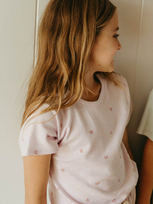 Girl wearing a light pink t-shirt with subtle floral patterns against a neutral background