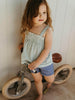 Young girl standing next to a balance bike indoors