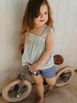 Young girl standing next to a balance bike indoors