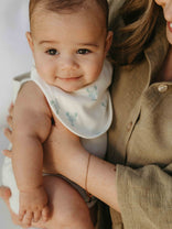 Baby wearing a bib being held by a person