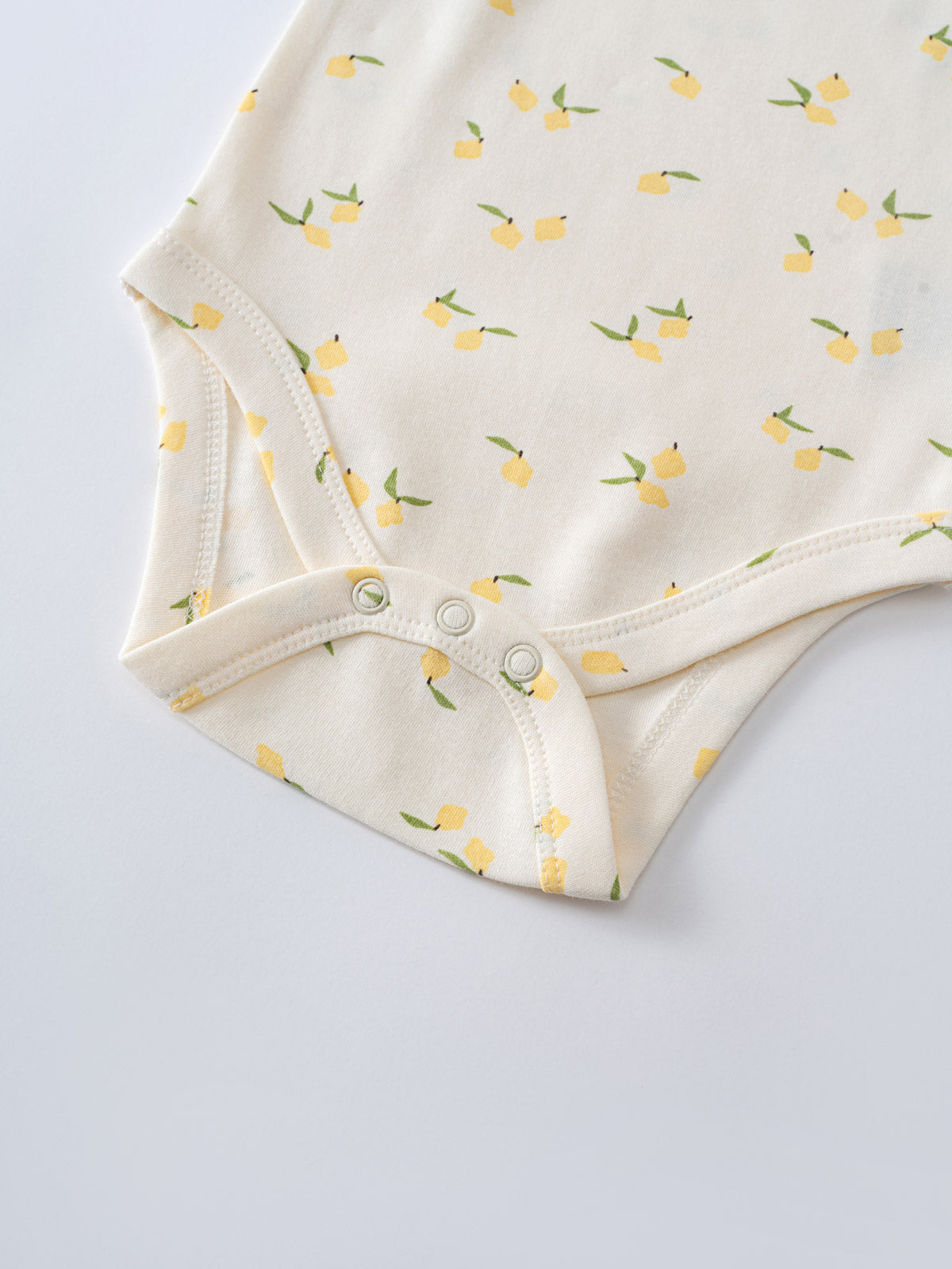 Close-up of cream baby bodysuit with yellow lemon print and snap closures Sleeveless Bodysuit - Lemons Baby girl