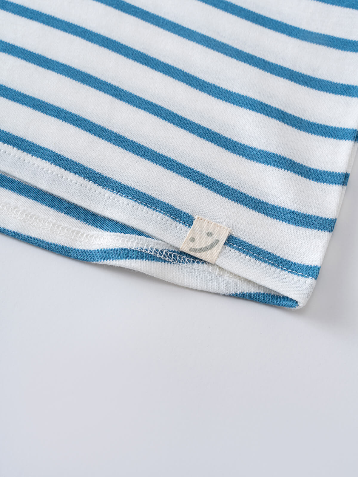 Close-up of a blue and white striped shirt hem with small label tag Sleeveless Tee - Blue Stripe Boys
