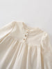 Close-up of a cream-colored blouse with buttons on a light gray background Three Button Blouse - Ecru Girls