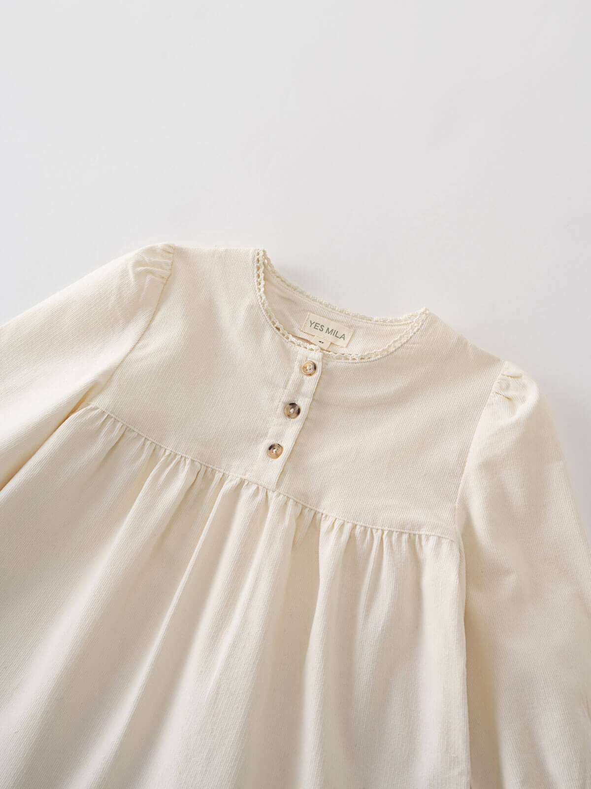 Close-up of a cream-colored blouse with buttons on a light gray background Three Button Blouse - Ecru Girls