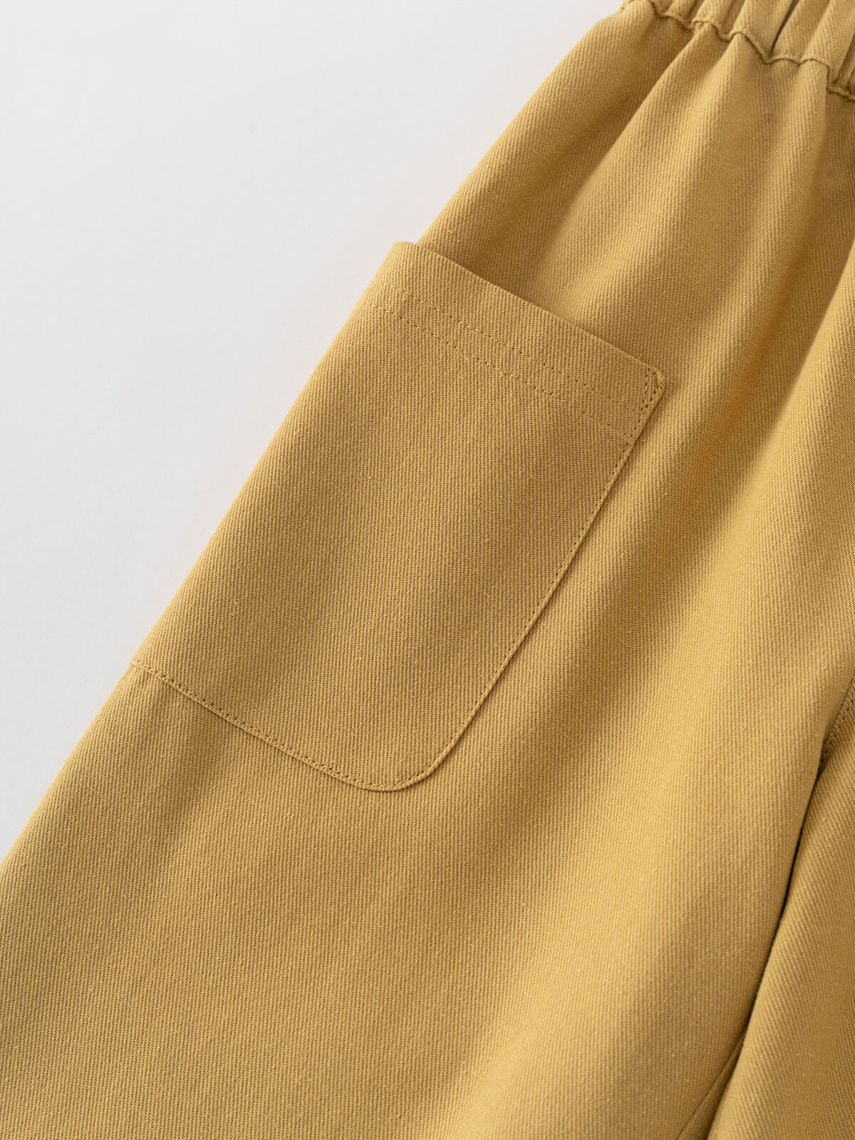 Close-up of mustard yellow pants with a pocket on a light gray background Twill Pants - Golden Pear Boys