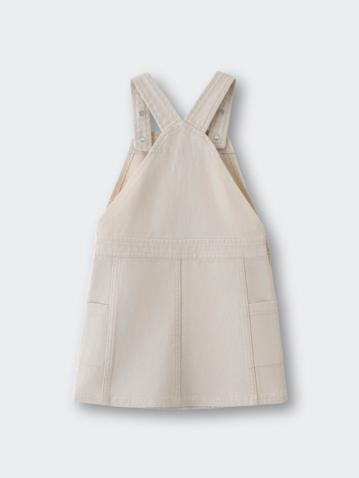 Beige overall dress with front pockets and adjustable straps laid flat Twill Pinafore Dress - Salt Girls