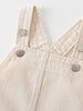 Close-up of cream-colored fabric with silver snap buttons and crossed straps Twill Pinafore Dress - Salt Girls