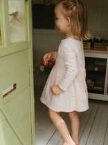 Young girl in a light dress standing inside a playhouse.