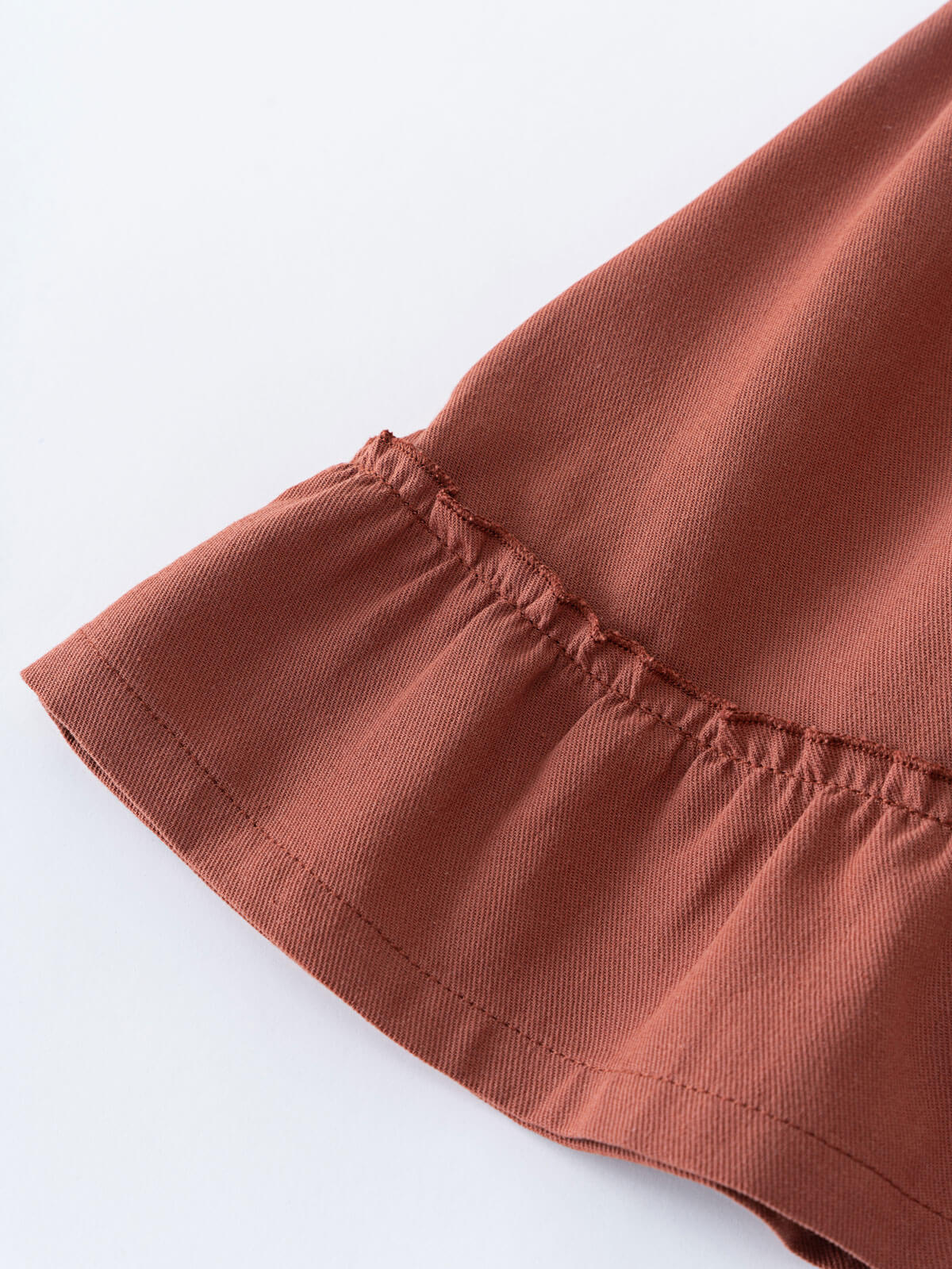 Close-up of rust-colored fabric with elastic waistband and gathered stitching detail Woven Skirt - Rosehip Girls