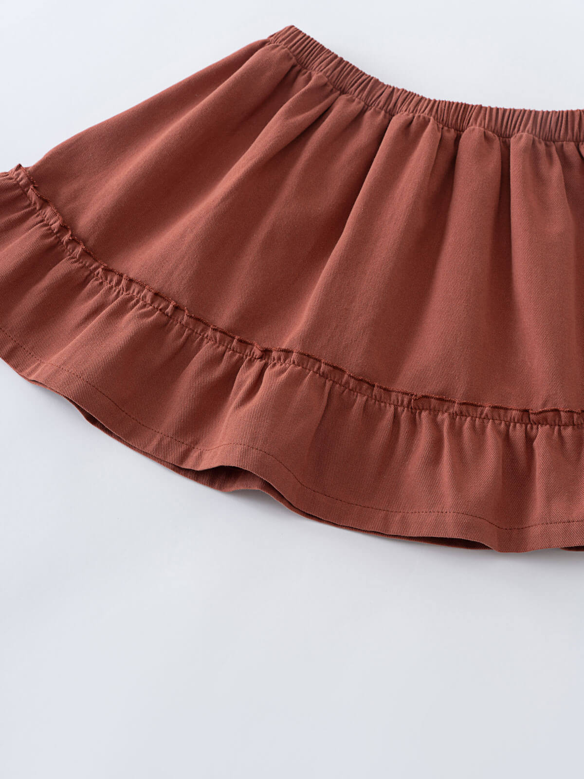 Close-up of a rust-colored skirt with elastic waistband and tiered ruffle hem Woven Skirt - Rosehip Girls