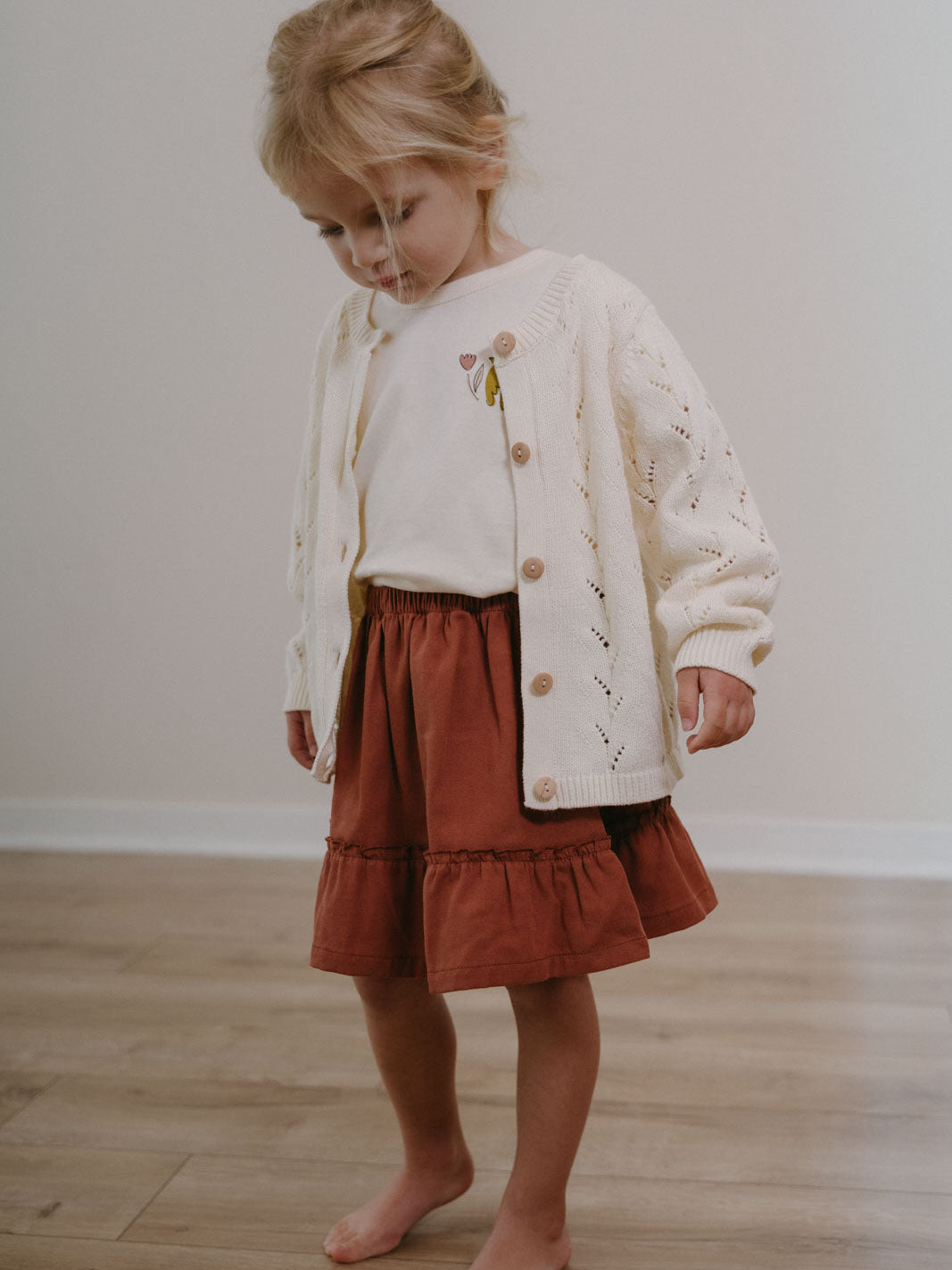 Young girl wearing cream cardigan and rust-colored tiered skirt standing barefoot Woven Skirt - Rosehip Girls