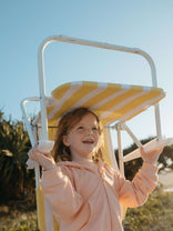 Girl holding a beach chair wearing a pink hoodie on a sunny day